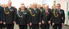 Strażacy w mundurach stoją w szeregu.