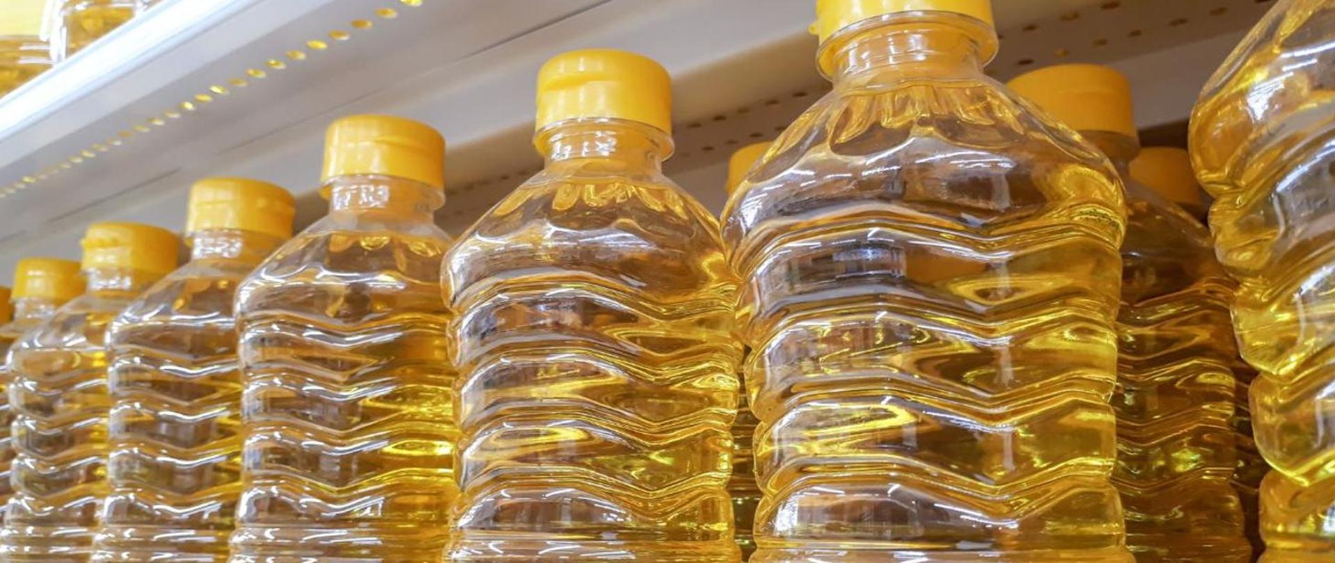 grafika przedstawiająca olej w plastikowych butelkach znajdujący się na półce. 