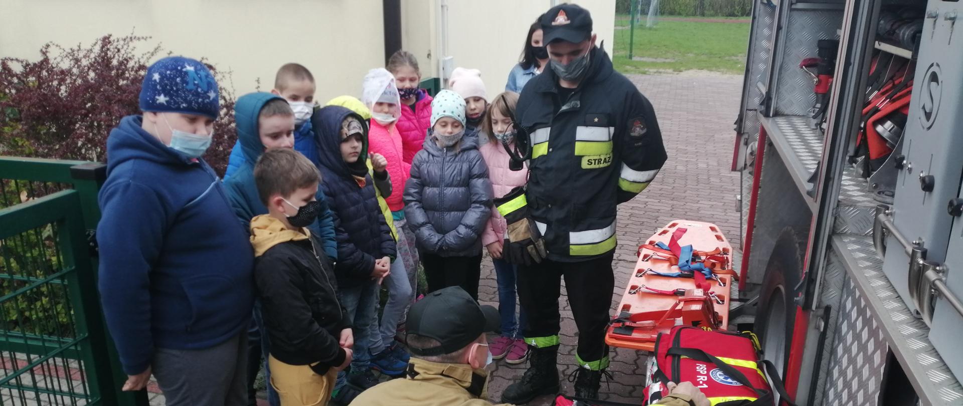 Strażak omawia zasady bezpieczeństwa, prezentuje sprzęt strażacki