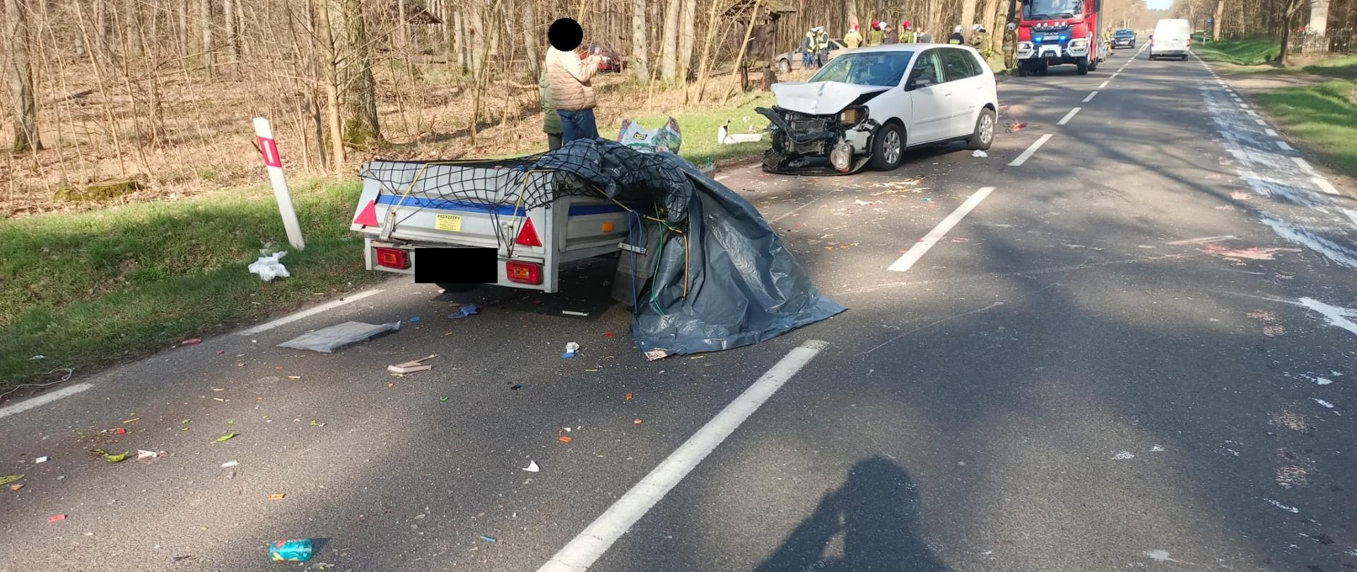 Uszkodzona przyczepka i biały samochód na drodze