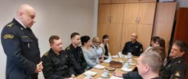 Strażacy zasiadający przy stole w trakcie spotkania wigilijnego.