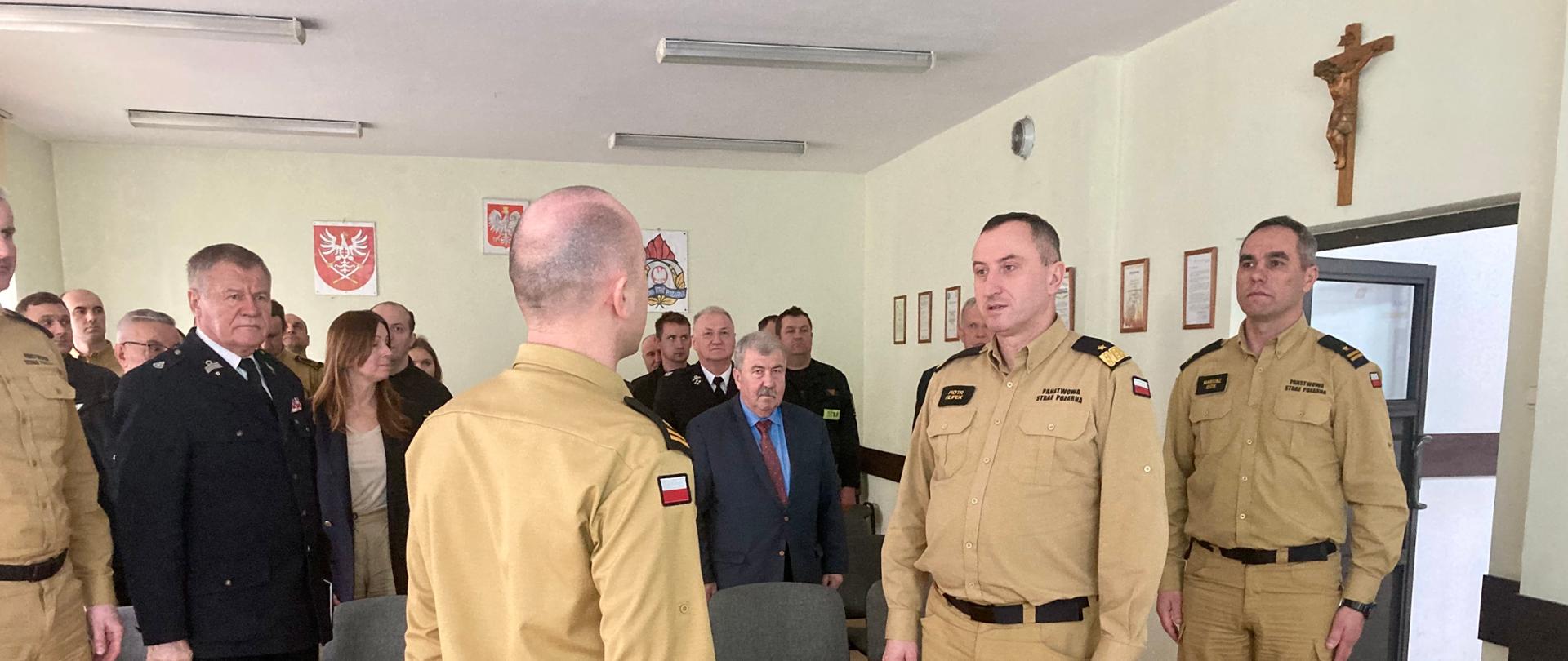 Meldunek o gotowości do narady składa z-ca komendanta powiatowego PSP Małopolskiemu Komendantowi Wojewódzkiemu PSP. Wszyscy w mundurach służbowych. W tle zaproszeni goście.