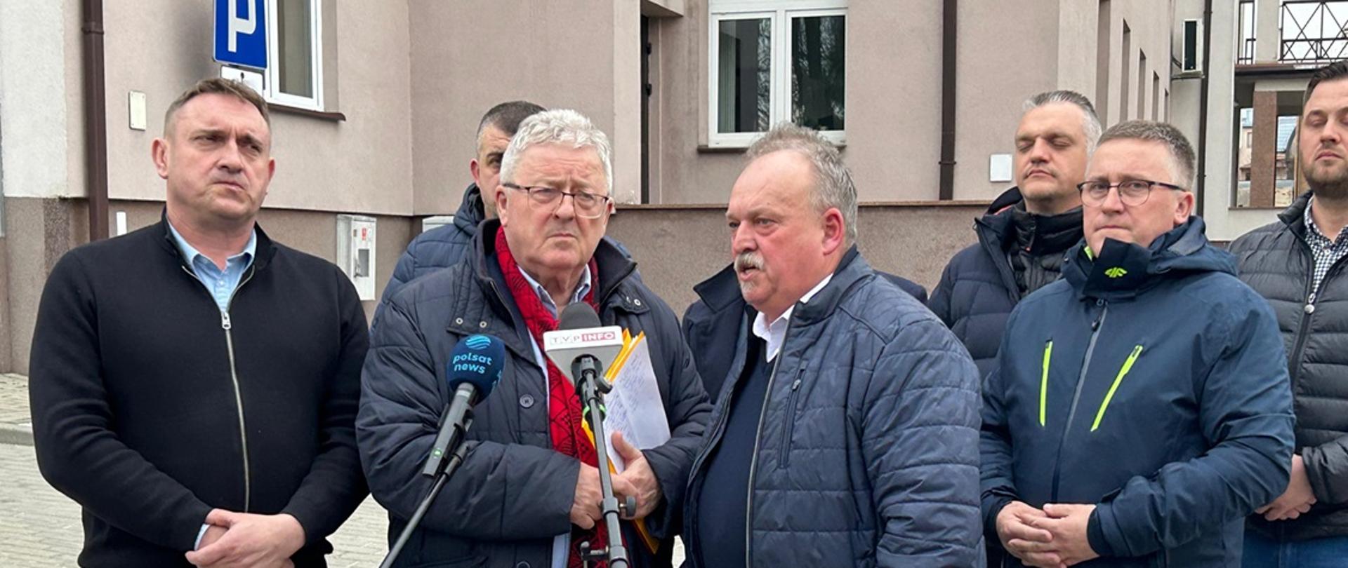 minister Czesław Siekierski stojący przy mikrofonach wraz z protestującymi rolnikami
