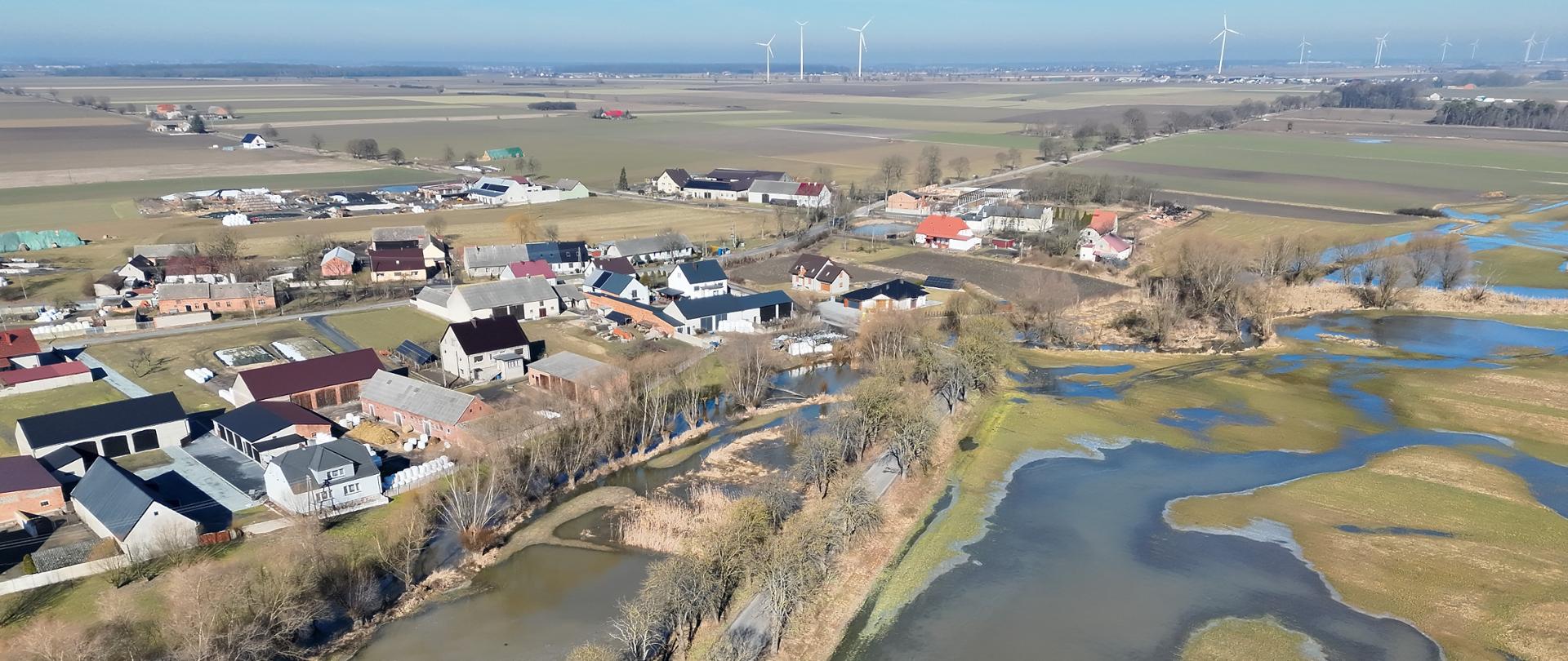 Zdjęcie przedstawia widok z lotu ptaka na tereny zalane wodą w okolicy budynków mieszkalnych.