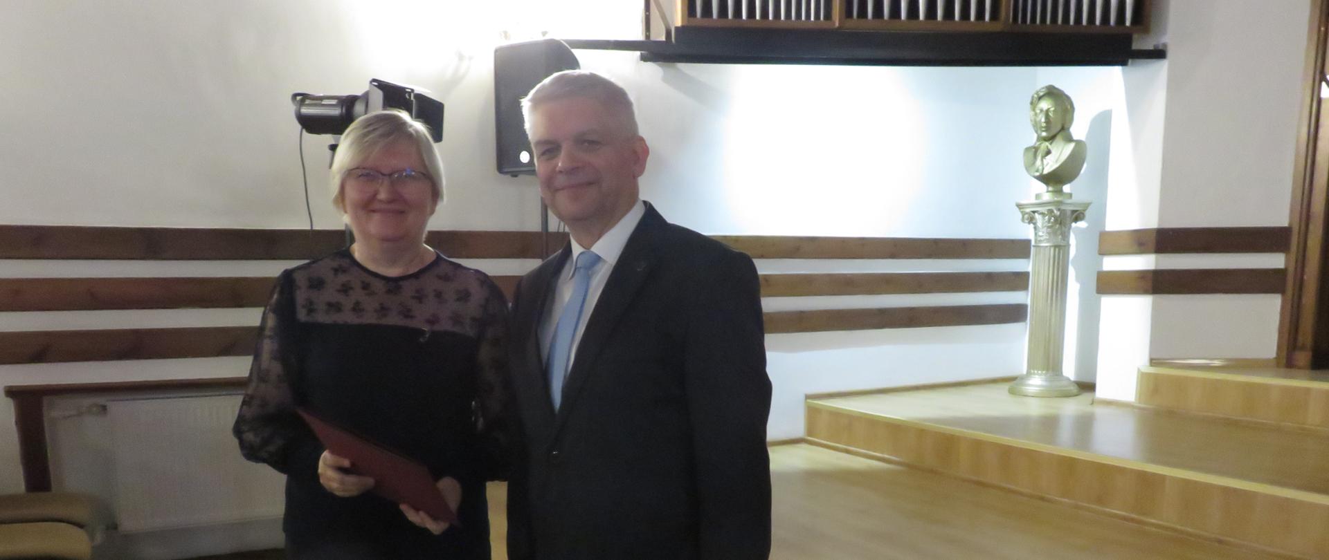 Laureatka nagrody Hanna Buczkowska-Bartczak stoi z dyrektorem Krzysztofem Pydyńskim, przed estradą.