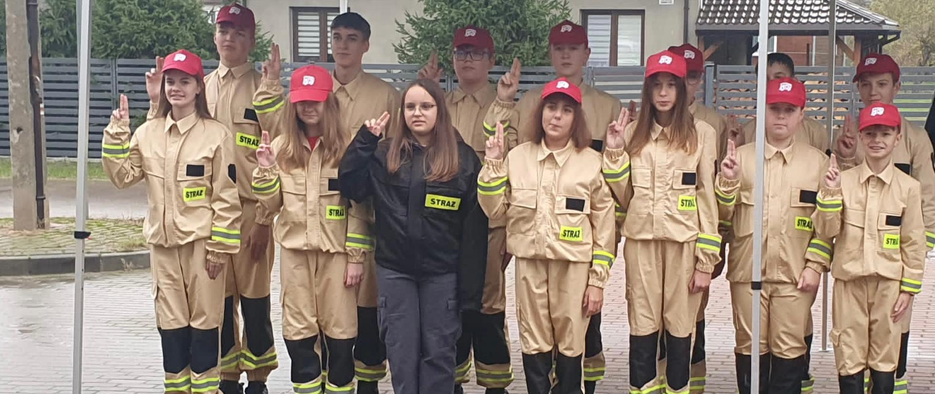 14 członków Młodzieżowej Drużyny Pożarniczej działającej przy Ochotniczej Straży Pożarnej w trakcie składania ślubowania.