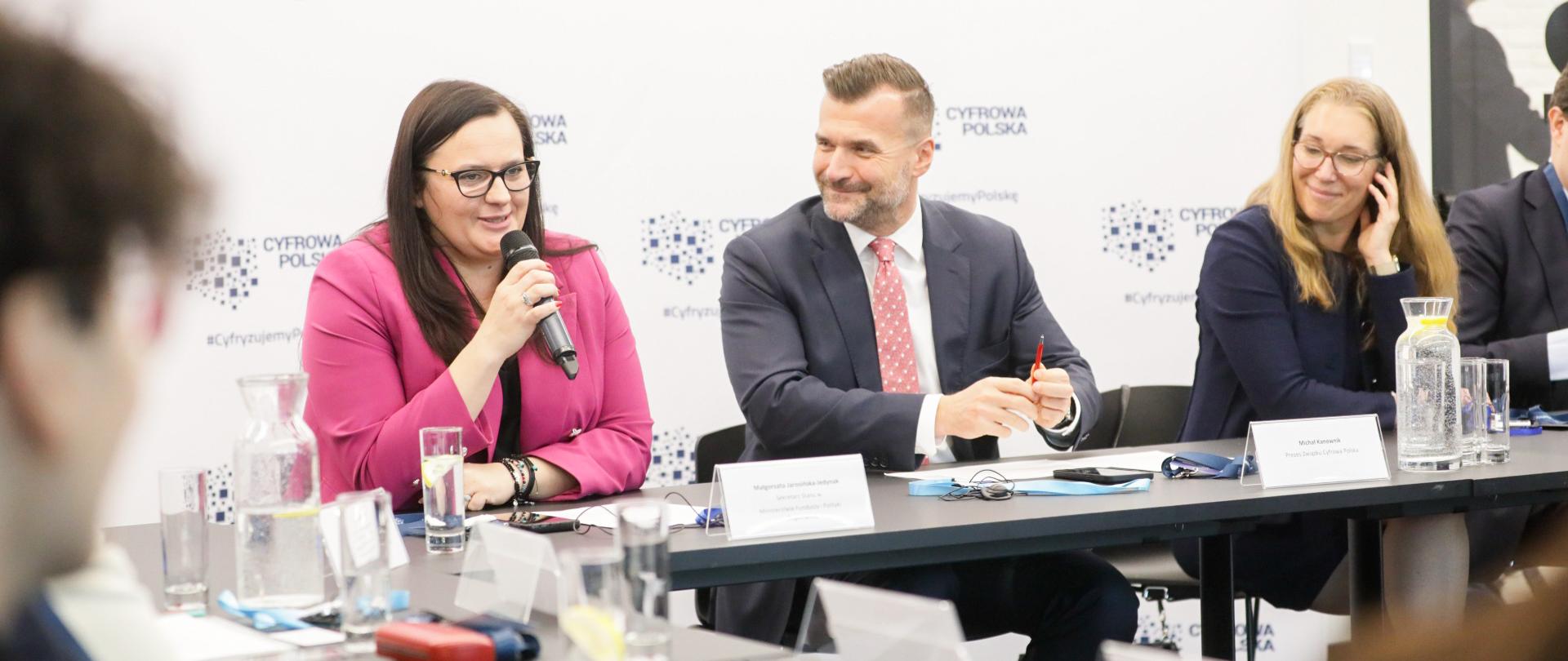 Przy stole siedzi grupa osób. Pierwsza z lewej wiceminister Małgorzata Jarosińska-Jedynak z mikrofonem.