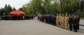 strażacy druhowie politycy i zaproszeni goście stoją na bokach placu w czasie uroczystości