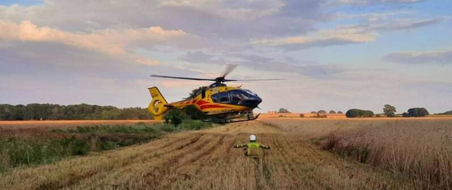 Zdjęcie przedstawia helikopter lądujący na polu.