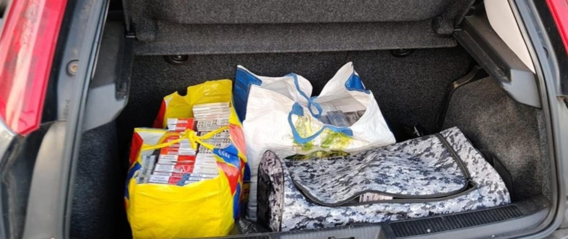 Kartony z papierosami ułożone w bagażniku auta. 
