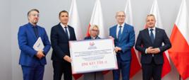 
Grupa ludzi w Sali konferencyjnej na tle biało-czerwonych flag
