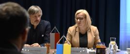 Zdjęcie przedstawia uczestników spotkania w sali konferencyjnej. Na drugim planie widać flagi Polski i Ukrainy
