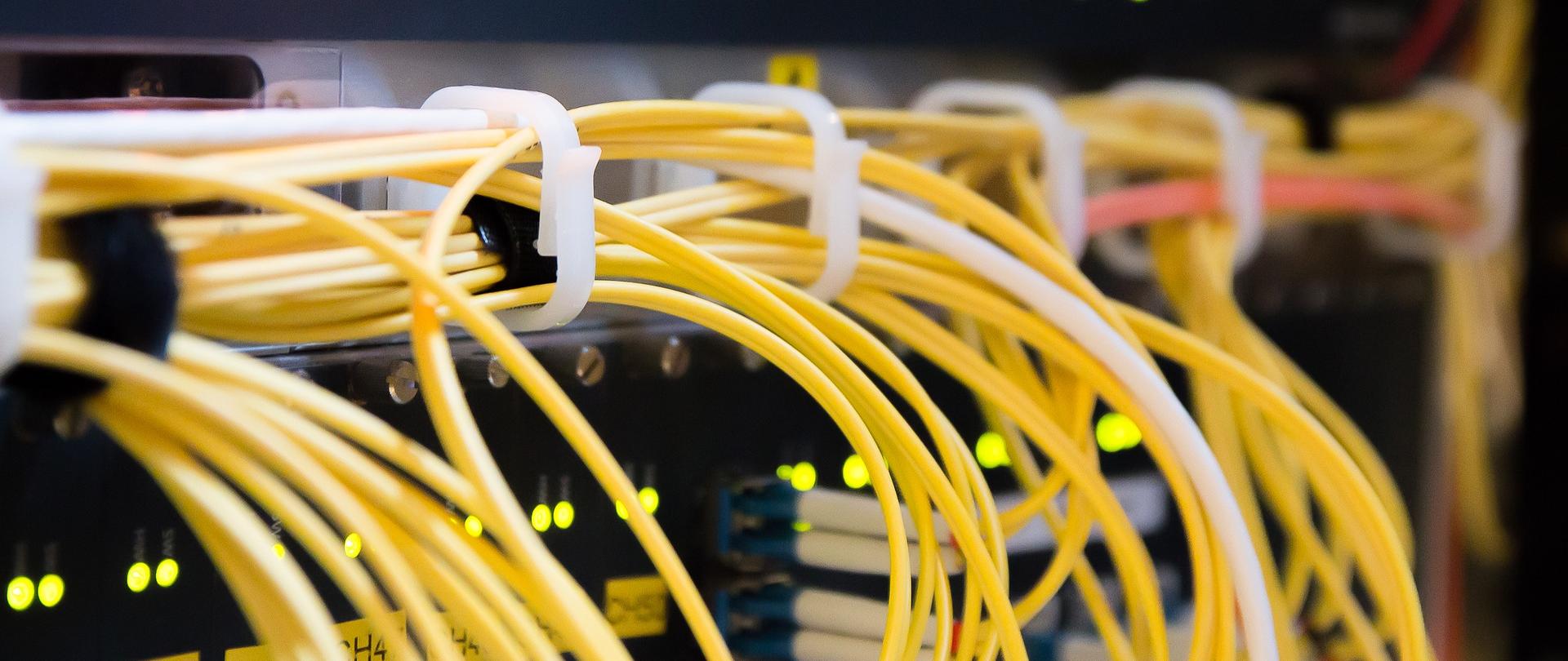 Żółte kable wystające z urządzenia typu modem.