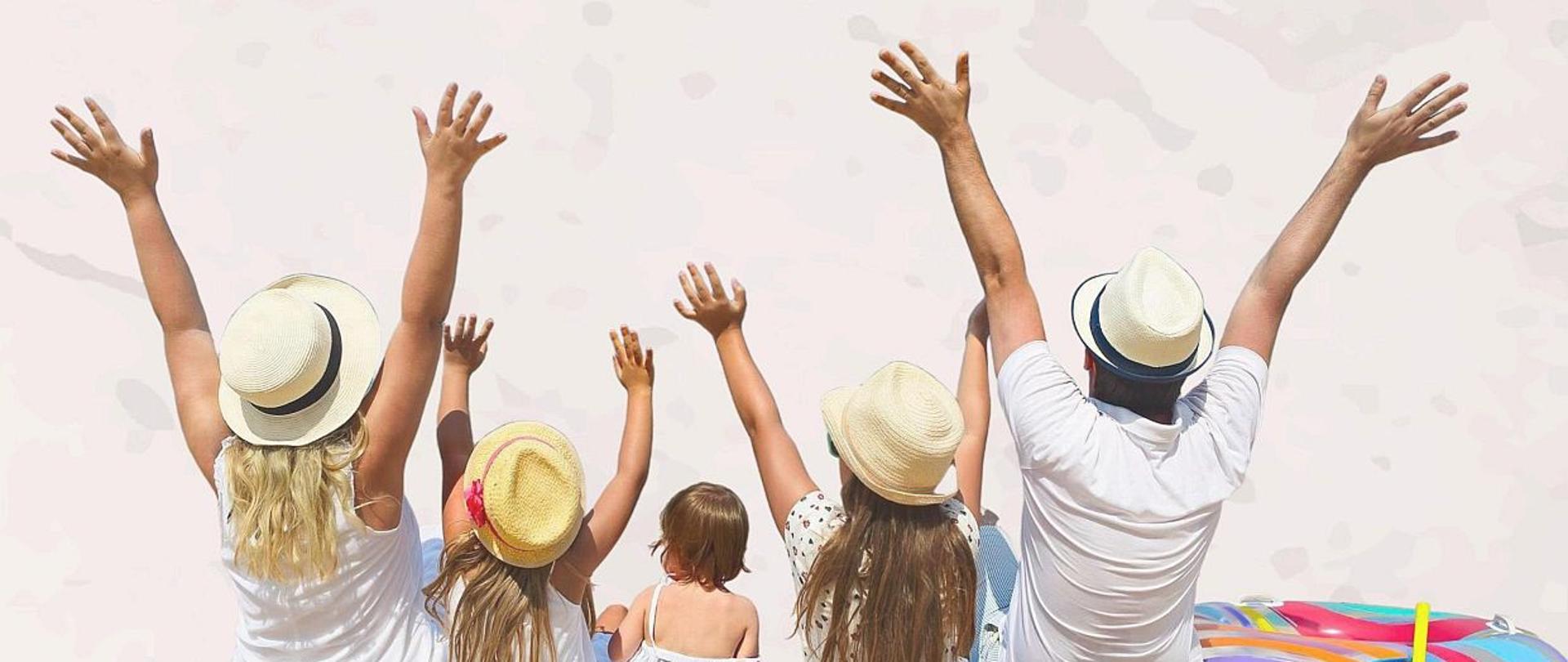 Obraz przedstawia napis bezpieczne wakacje z sanepidem poniżej na zdjęciu mamy 2 osoby dorosłe kobietę z lewej i mężczyznę z prawej, pomiędzy nimi jest 3 dzieci 2 starsze i 1 młodsza dziewczynka