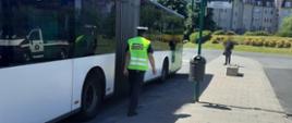 Inspektor ITD kontroluje stan techniczny autobusu miejskiego na jednej z pętli końcowych w Szczecinie. W tle widoczne bloki.