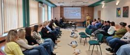 Komendant omawia pracownikom starostwa przy pomocy prezentacji zagrożenia występujące w budynkach. Na środku leżą fantomy do udzielania pierwszej pomocy 