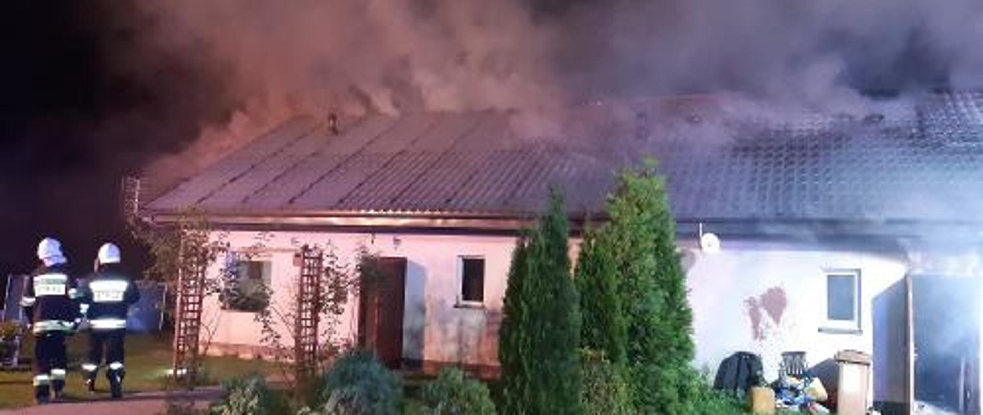 Budynek mieszkalny. Wydobywający się z dym budynku. Na zdjęciu strażacy udający się do działań ratowniczo - gaśniczych