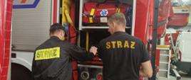 Strażacy przy samochodzie gaśniczym sprawdzają sprzęt