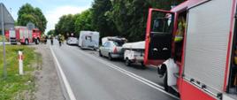 Na zdjęciu widać drogę na której doszło do kolizji czterech samochodów. Za rozbitymi samochodami stoi strażacki samochód. Na wysokości pierwszego auta widać drugi strażacki samochód przy którym stoją strażacy