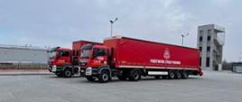 Zdjęcie przedstawia dwa tiry transportowe Państwowej Straży Pożarnej ustawione na placu wewnętrznym Jednostki Ratowniczo-Gaśniczej nr 3 w Rzeszowie