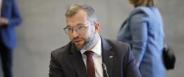 Minister funduszy i polityki regionalnej Grzegorz Puda na polsko-czeskich konsultacjach międzyrządowych, minister siedzi przy stole z mikrofonem