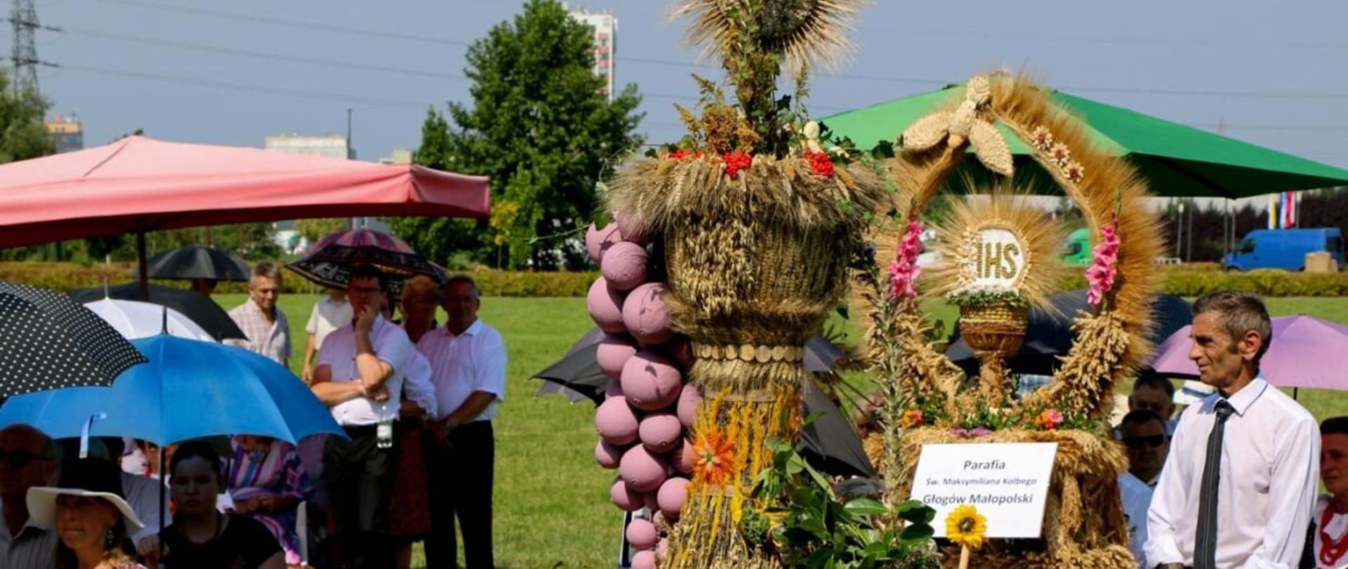 Wieniec dożynkowy i uczestnicy dożynek w tle