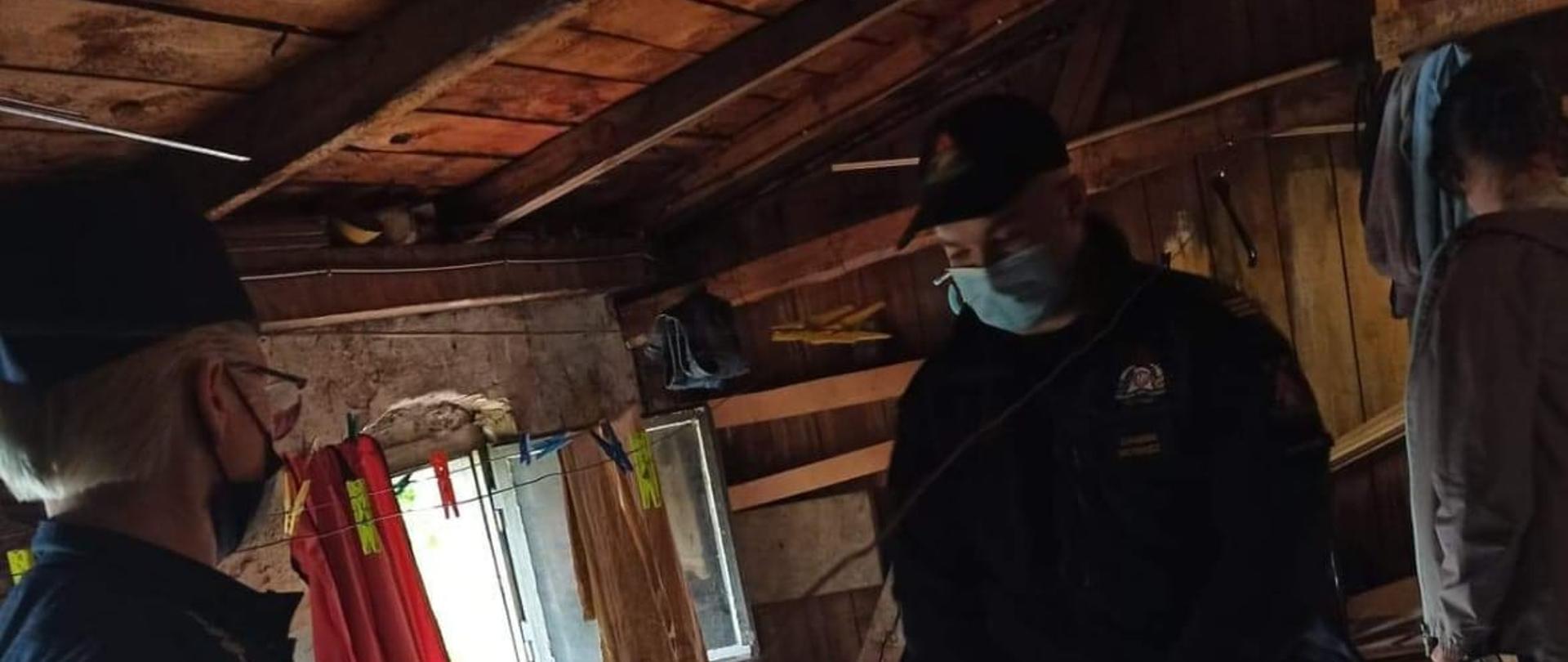 Zdjęcie przedstawia policjanta oraz strażaka, znajdujących się na strychu przeprowadzają kontrole.