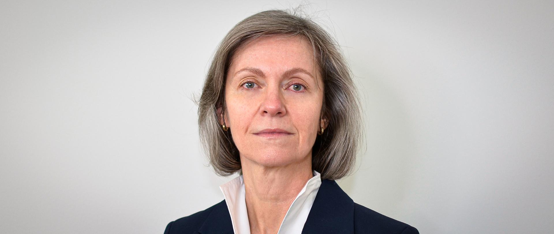 Kobieta w ciemnej marynarce, białej bluzce i włosami do ramion