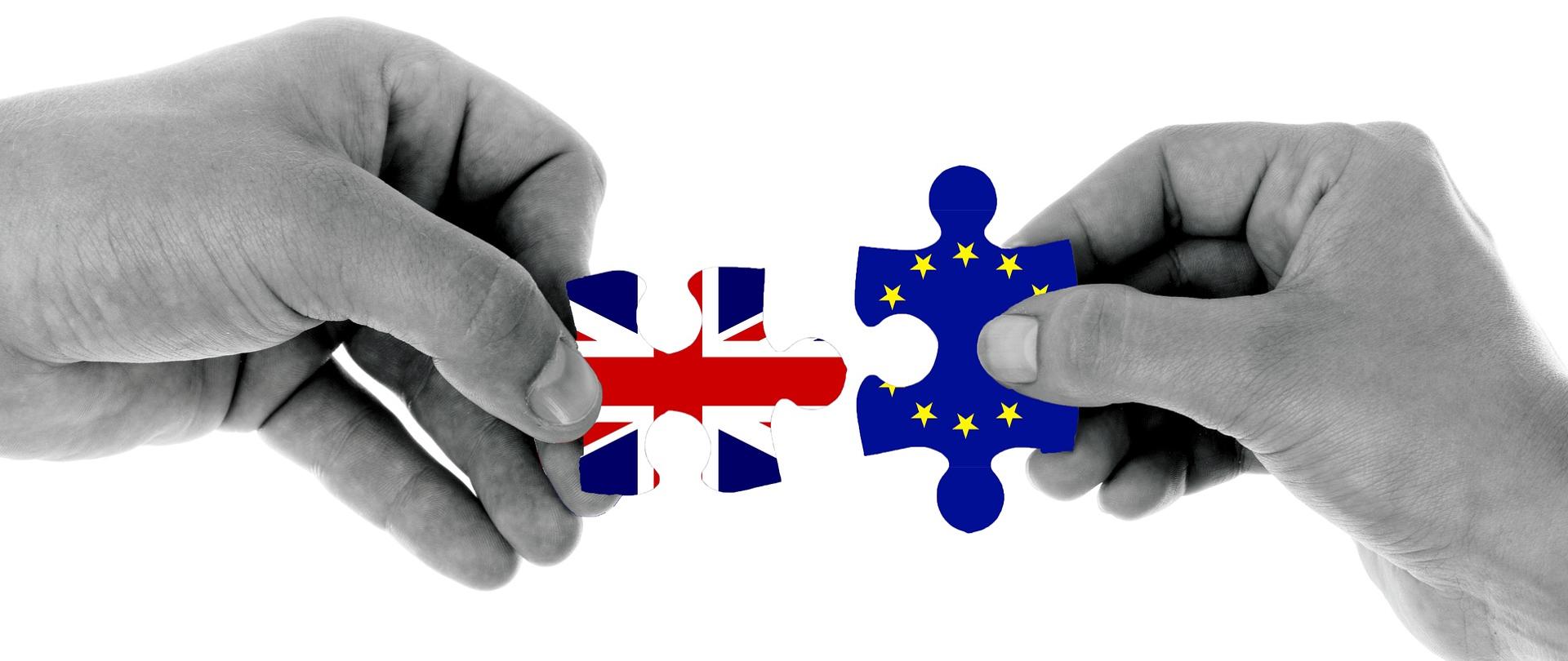 dwie ręce trzymające puzzle z flagami Wielkiej Brytanii i Unii Europejskiej.