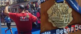 Zdjęcie przedstawia na pierwszym planie biegacza stojącego na mecie maratonu, odwróconego tyłem w koszulce z napisem KP PSP w Wałczu. Powyżej widać bramę mety z napisem nazwy jubileuszowego wydarzenia. Sportowiec ma na ramieniu przewieszony medal otrzymany po ukończeniu maratonu. 