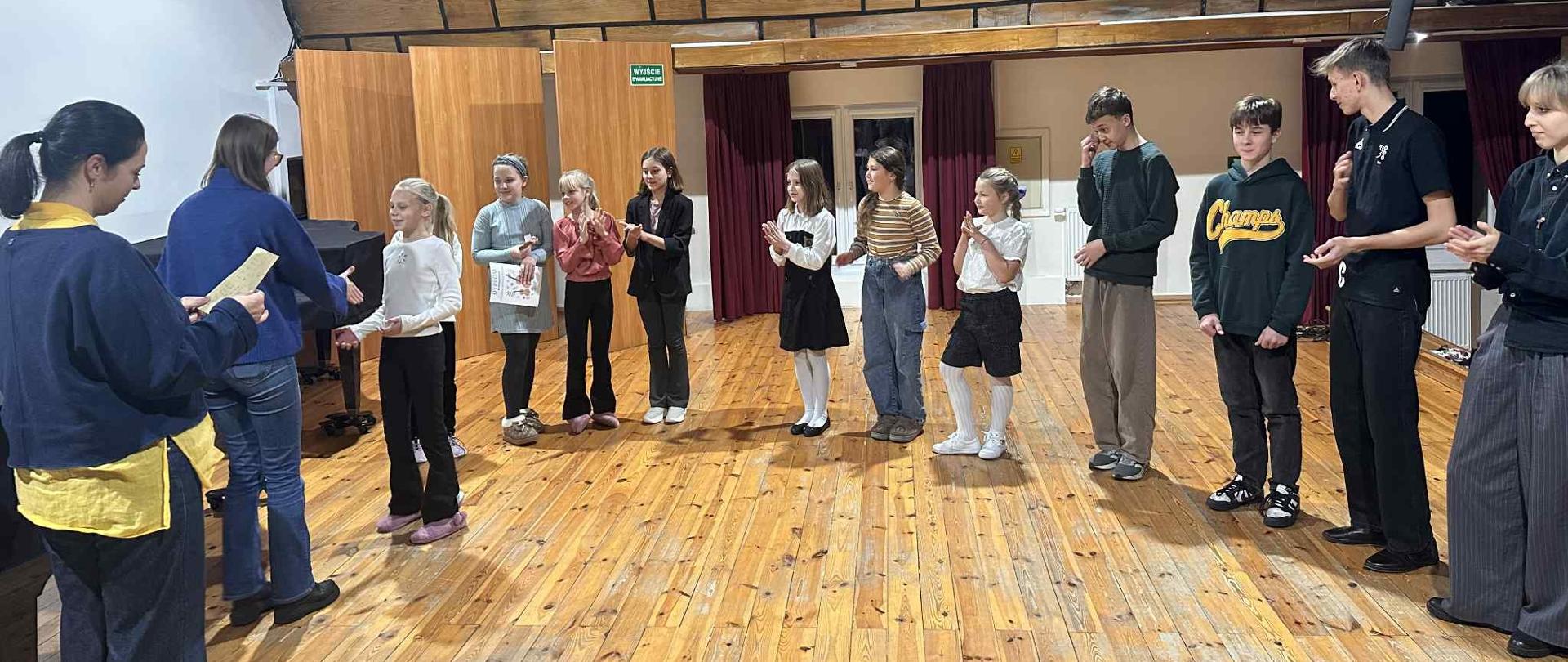 Uczniowie stoją w kolejce do odbioru dyplomów