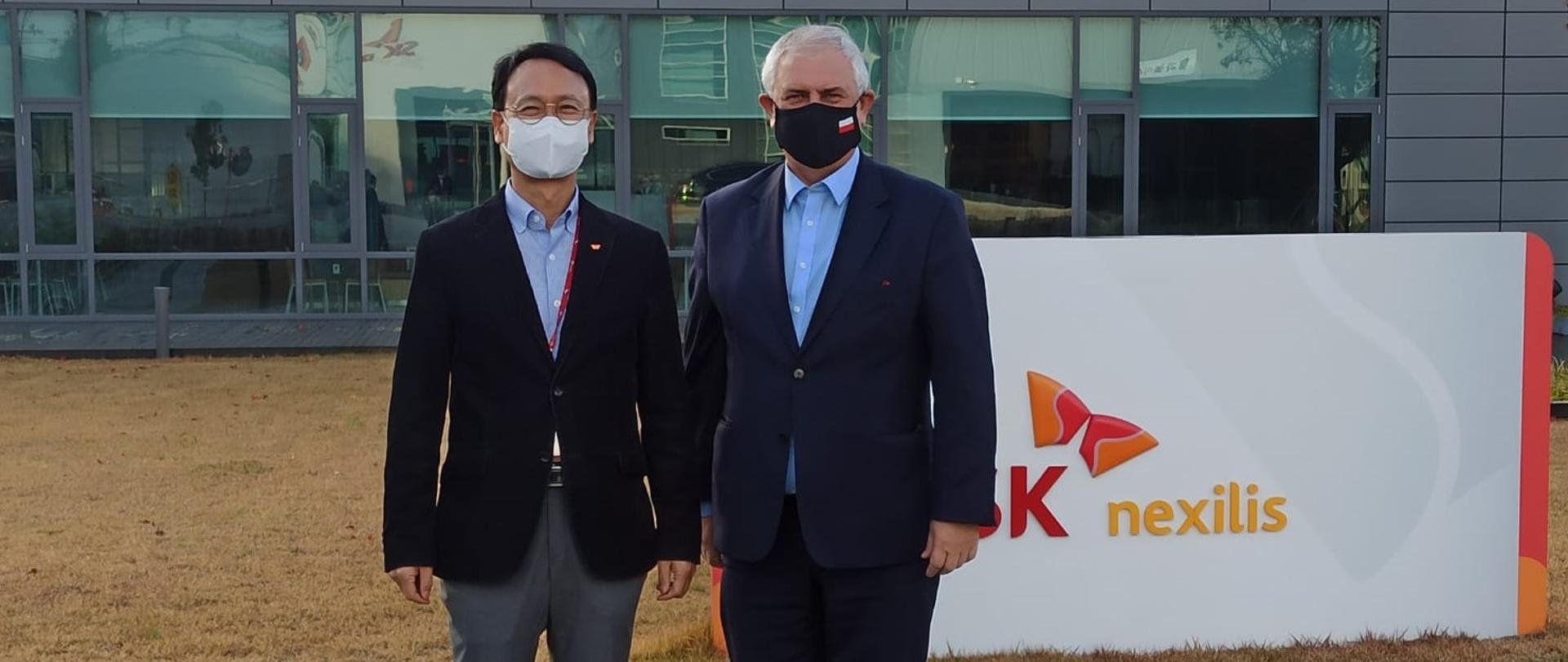 Deputy Minister Grzegorz Piechowiak and the president of SK Nexilis are standing in front of the factory building 