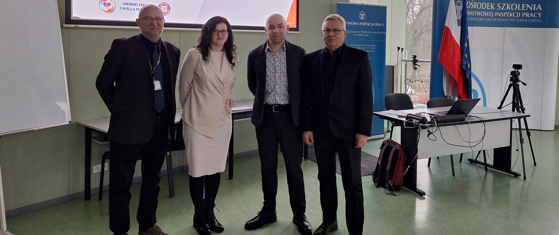 Osoby stojące na sali wykładowej