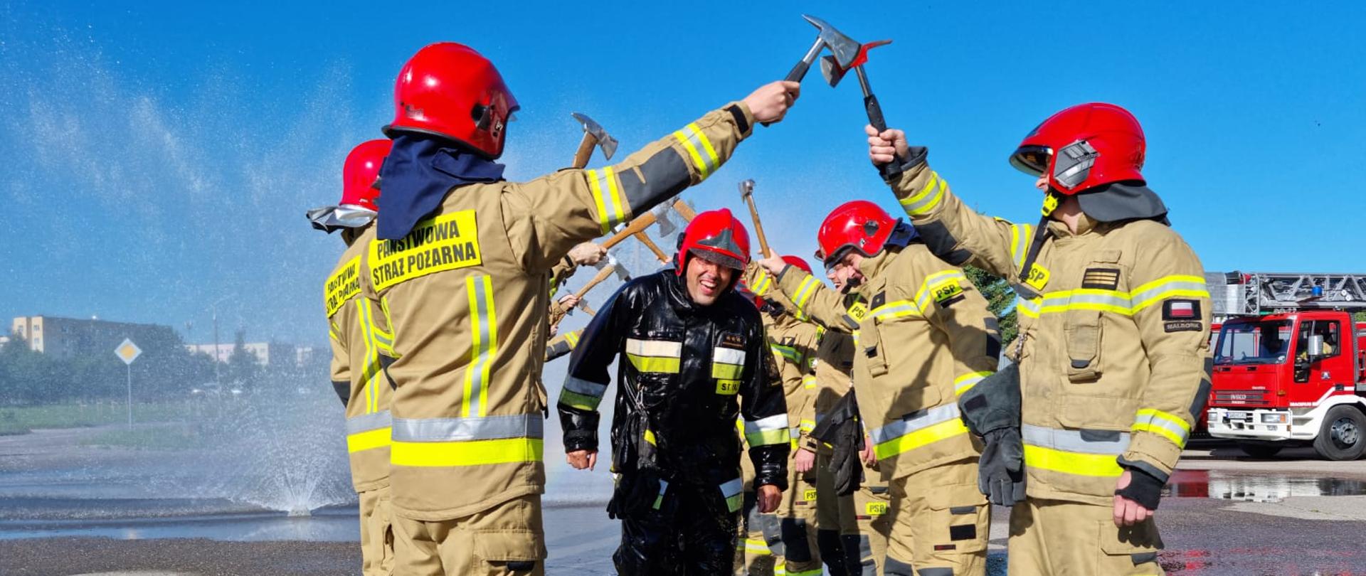 Fotografia przedstawia dowódcę zmiany maszerującego we mgle wodnej podczas szpaleru pożegnalnego.