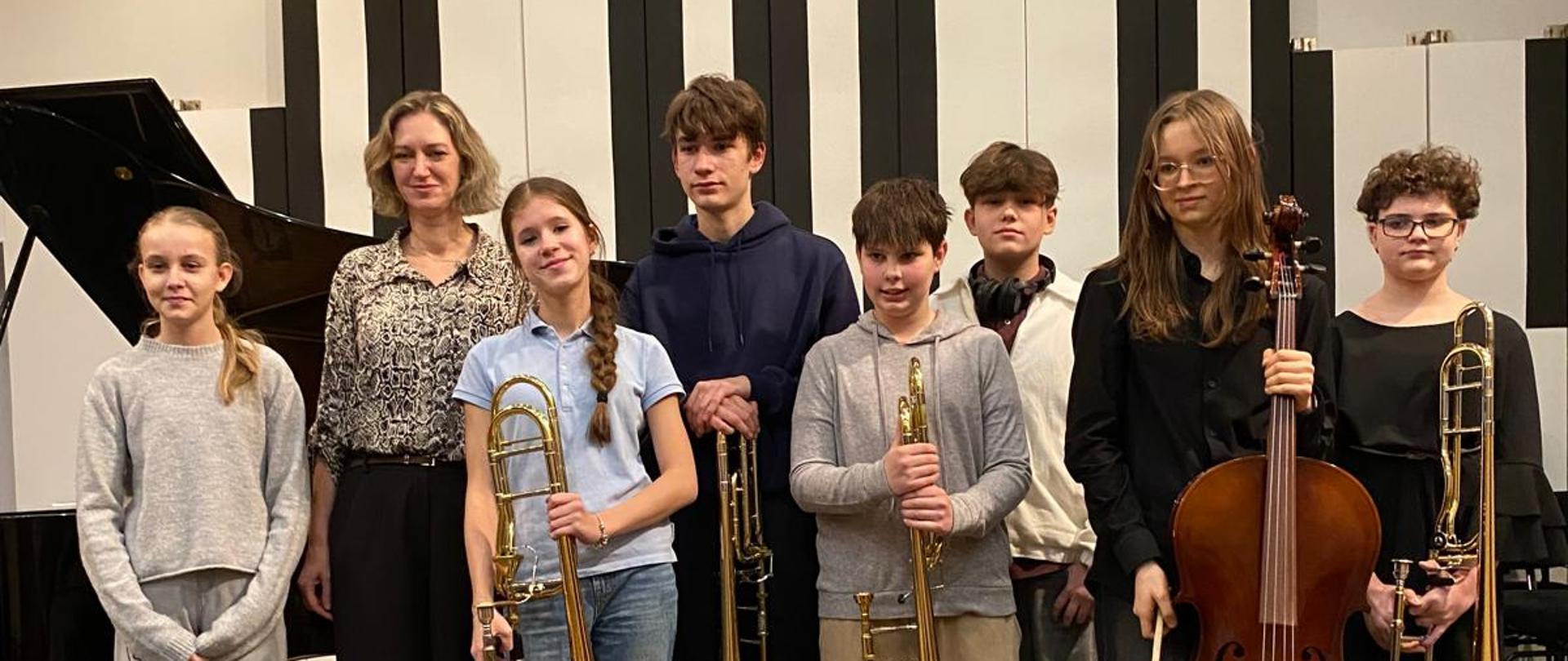 Wszyscy wykonawcy stoją na scenie z nauczycielką.