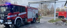 Na zdjęciu dwa samochody ratowniczo- gaśnicze straży pożarnej. Widoczny jest również strażak. 