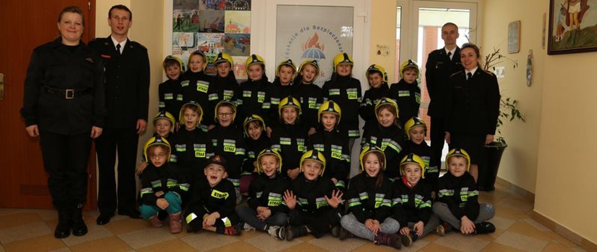 Zdjęcie przedstawia pamiątkowe zdjęcie uczniów wraz ze strażakami