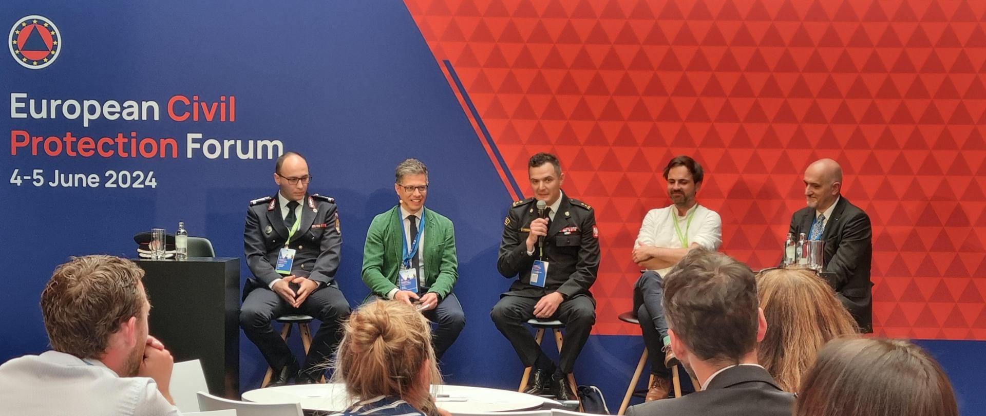 Grupa osób dyskutuje podczas konferencji. 