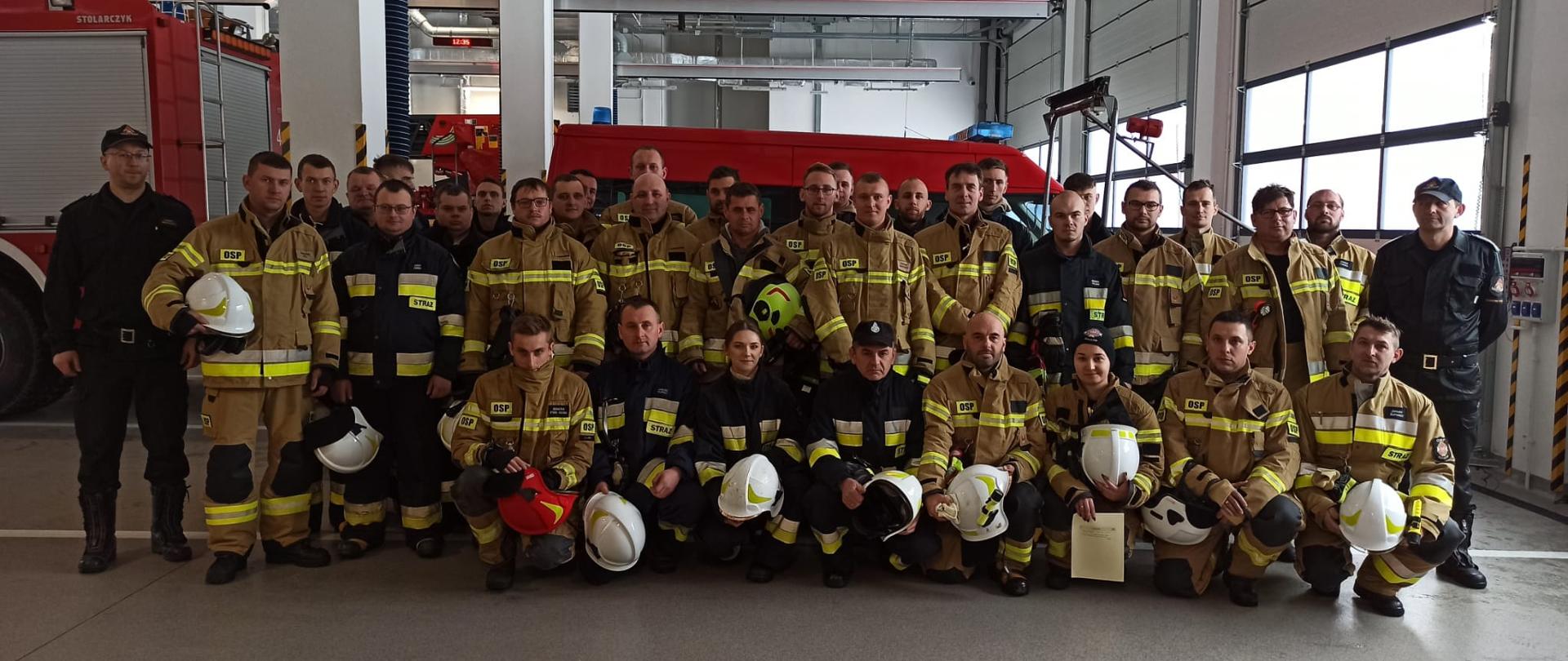 Na zdjęciu strażacy OsSP po egzaminie stoją na garażu