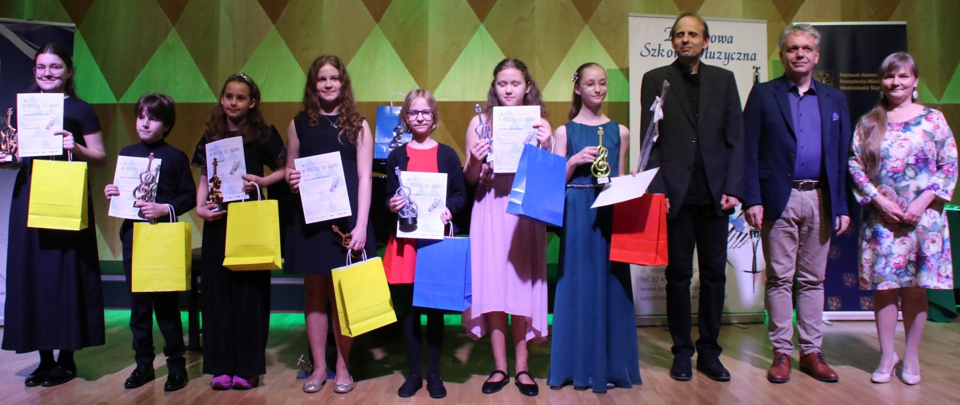 grupa uczniów i jurorzy konkursu na scenie sali koncertowej