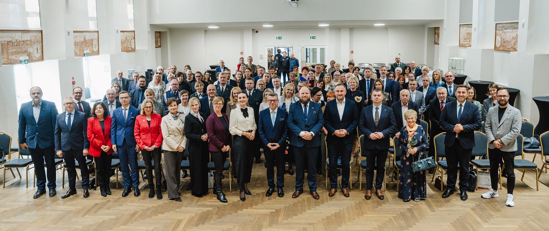 Grupa osób stoi w dużej sali i pozuje do zdjęcia