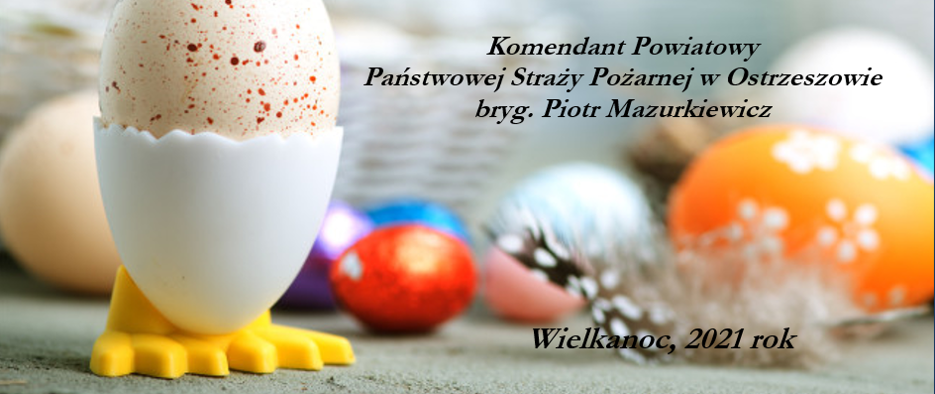 Kartka z życzeniami Wielkanocnymi od Komendanta Powiatowego Państwowej Straży Pożarnej w Ostrzeszowie. W tle motyw świąteczny: jajeczka, koszyczek, kolorowe pisanki.