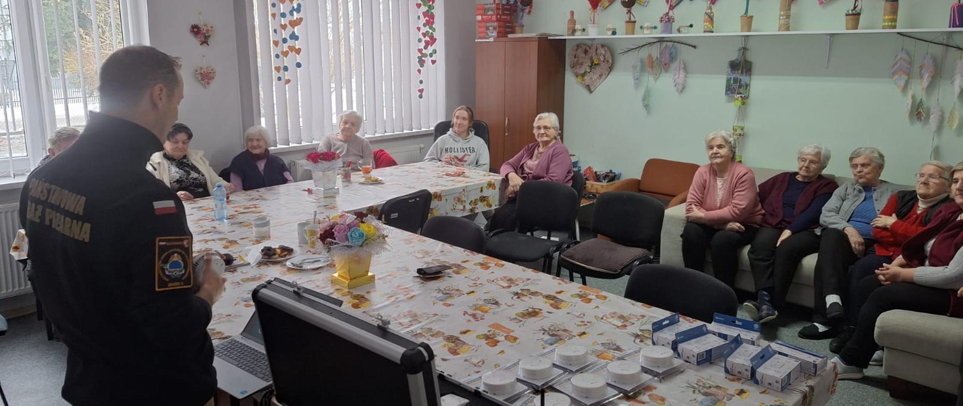 Funkcjonariusz PSP prezentuje seniorom działanie czujek dymu i tlenku węgla