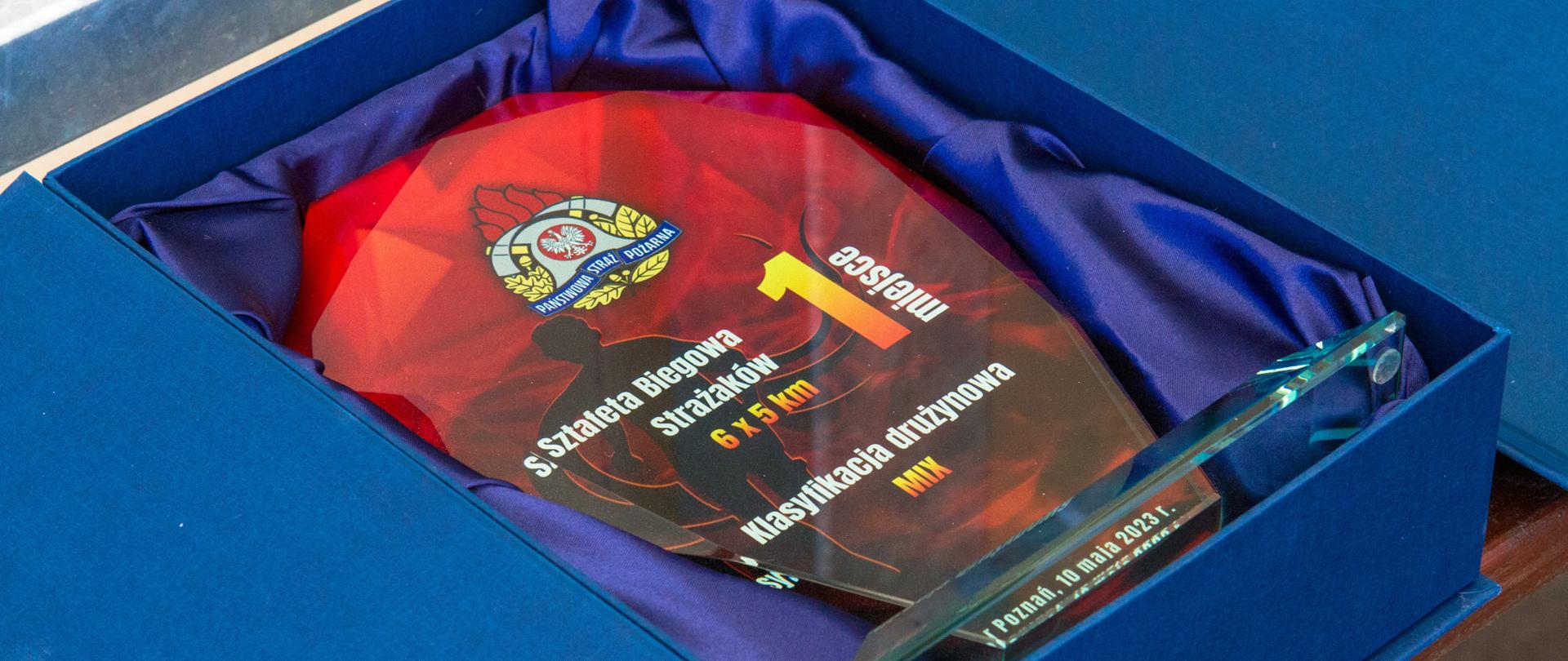 W granatowym pudełku statuetka czerwona z napisem Sztafeta Biegowa Strażaków 6x5 km klasyfikacja drużynowa mix 1 miejsce