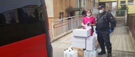 Strażak przekazuje środki ochrony indywidualnej personelowi medycznemu w punkcie sczepień 