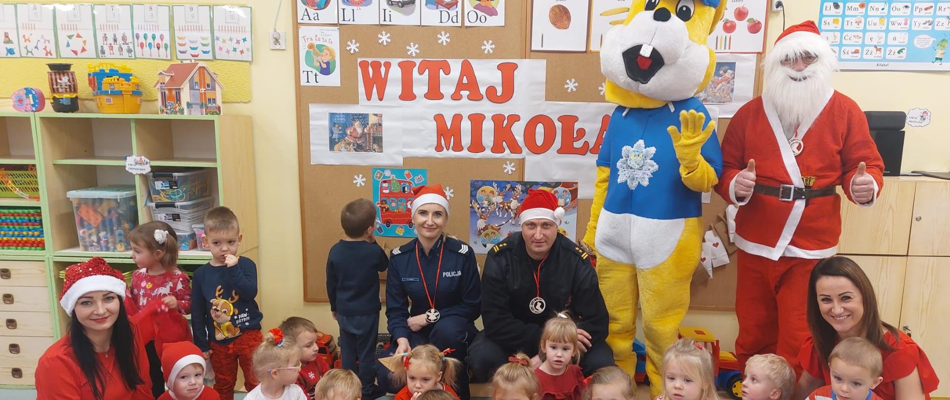 Na zdjęciu znajdują się dzieci w sali przedszkolnej ubrane na czerwono oraz kilka osób dorosłych 