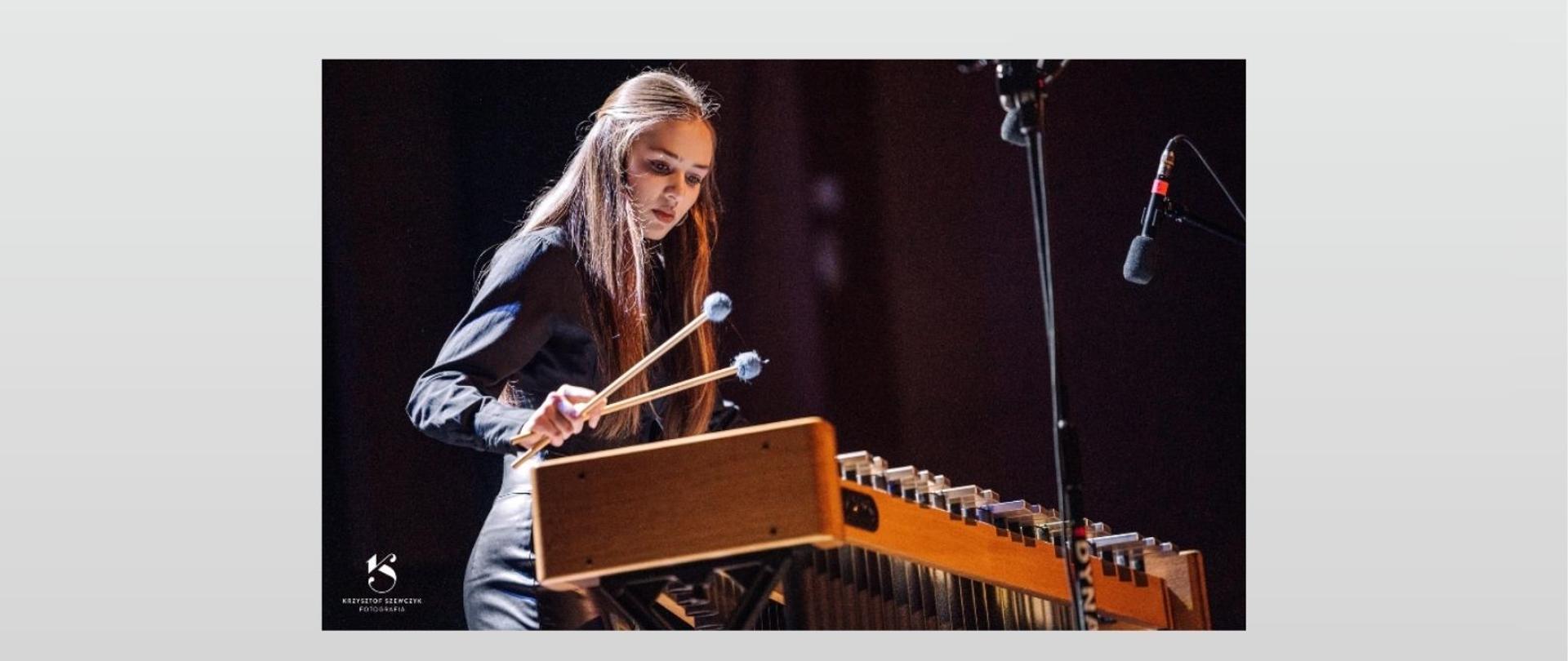 Tło szare, napisy w kolorze czarnym, na górze od lewej logo szkoły i napis Audycja Muzyczna. Centralnie widać imię i nazwisko wykonawczyni, nauczyciela oraz nazwę szkoły. Poniżej zdjęcie dziewczyny grającej na wibrafonie. Na dole po lewej program audycji, pod nim data, godzina i miejsce.