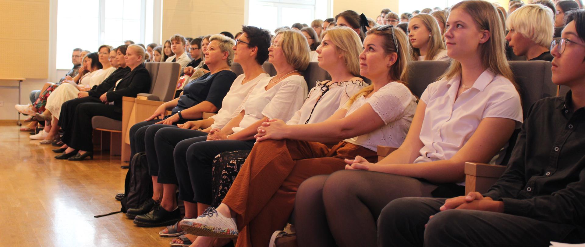 zdjęcie przedstawia publiczność zgromadzoną na miejscach siedzących widowni sali koncertowej