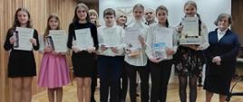 Zdjęcie przedstawia stojących na scenie laureatów Szkolnego konkursu na samodzielne przygotowanie utworu w roku szkolnym 2023/2024 wraz z jurorami