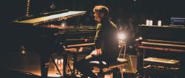Pianista siedzi przy fortepianie, po prawej stronie stoi pianino, w tle publiczność